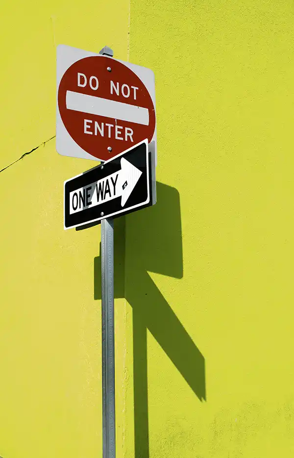 Streat sign on yellow background says "do not enter" and "one way"