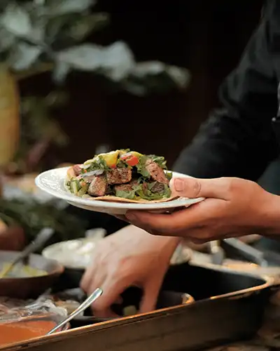A chef is holding a plate of colourful food