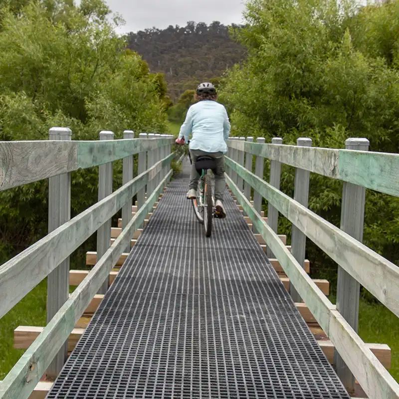 A woman is riding her bike over a brige on the North East Rail Trail