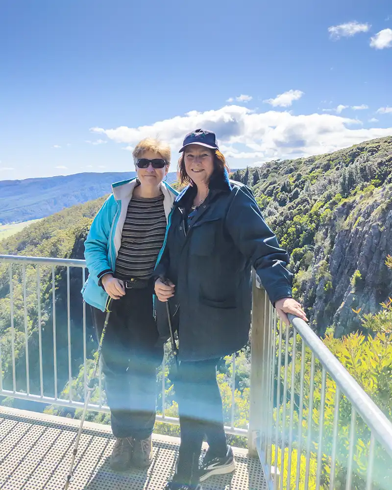 Two women standing on the Ralph Falls lookout with the mountains in the background