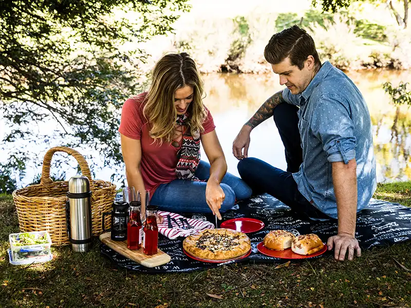 A young couple are picnicing on the banks of the Ringarooma River at Tin Dragon Cottages in North East Tasmania